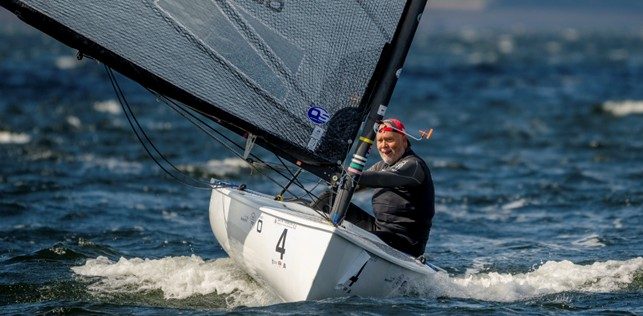 Smilende Finnjollesejler vinker fra båden
